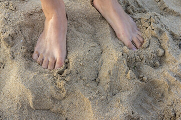 Girls' feet on the sand. Near the surf line.