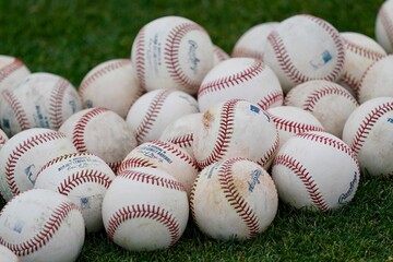 A collection of Major League Baseballs piled up on the infield grass.