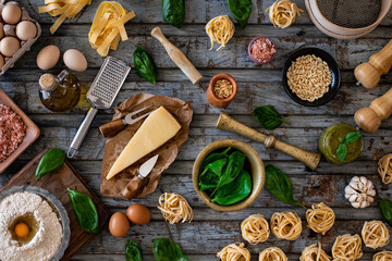 Hands of two women preparing pesto sauce with parmesan cheese, basil, pine nuts and other ingredients