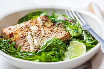 Chunks of fried tofu with green salad in white bowl. Asian cuisine, vegan food concept.
