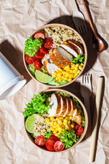 Chicken and quinoa salad with corn and tomatoes in craft eco bowl. Zero waste, to go food, recycling packaging, eco friendly concept.