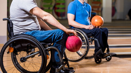 Two young disabled men in wheelchairs playing bowling in the club