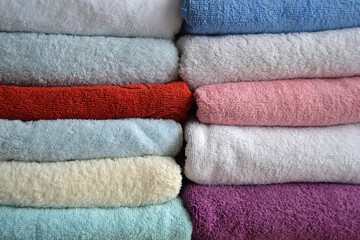 Multi-colored cotton terry towels are stacked. Home textile background