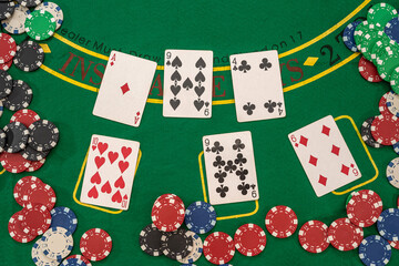  playing cards and casino poker chips on green table