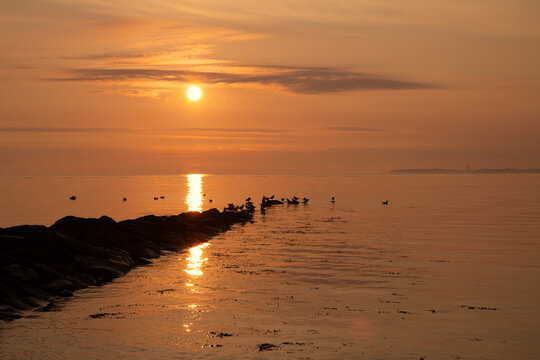 Scenic seascape at sunrise with orange sky, burial at sea