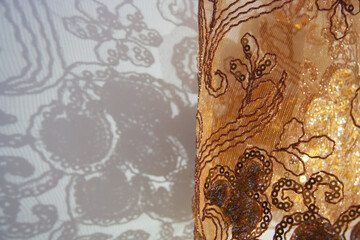 Shadow of floral pattern from orange transparent curtain. Decorated fabric with intricate...