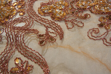 Detail of the transparent fabric with floral motifs, orange: decorated with intricate embroidery.