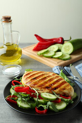 Salad with grilled chicken on gray textured table