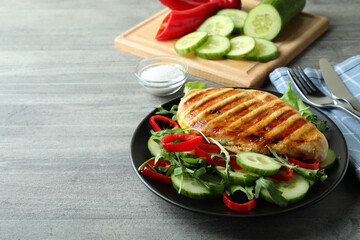 Salad with grilled chicken on gray textured table