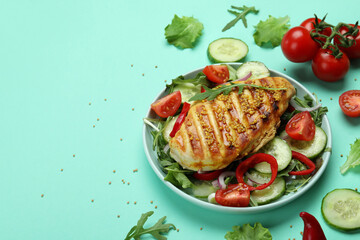Salad with grilled chicken on mint background