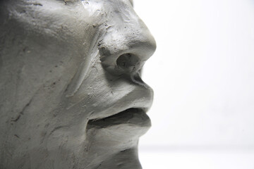 Female profile face, wet clay material, artwork in progress, on white background