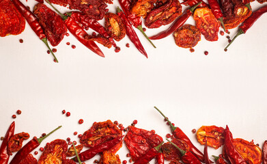 Peppers and tomatoes background. Dried hot chili peppers and red sun-dried tomatoes on a white plate. Spices and vegetables food minimal flat lay background concept