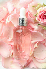 Bottle with rose essential oil on rose petals background