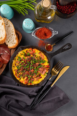Egg omelet with sausage and seasonings in a cast iron pan top view, vertical photo