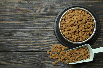 Pet bowl and scoop with feed on wooden background