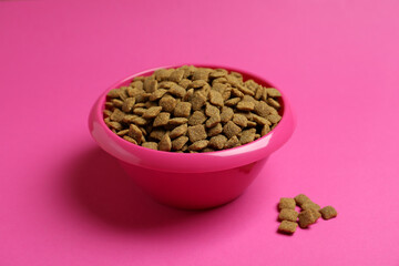 Pet bowl with feed on pink background