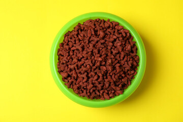 Pet bowl with feed on yellow background