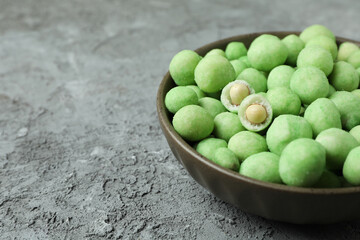 Bowl of wasabi nuts on gray textured background