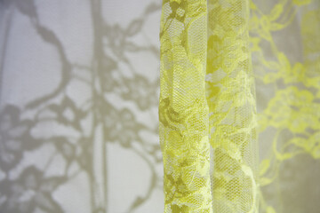 Sunlight on the wall with shadows from the yellow lace curtain. 