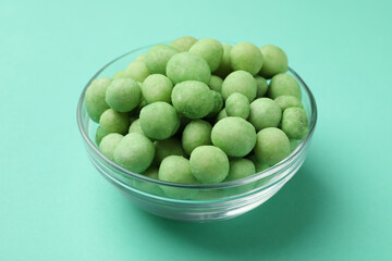 Bowl of wasabi nuts on mint background