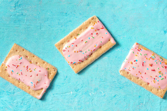 Pink pop tarts on a blue background, top shot of toaster pastry
