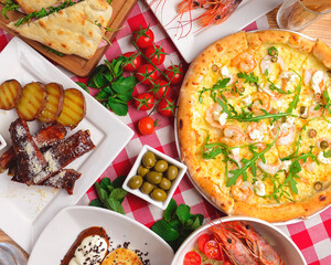Traditional Italian cuisine concept flat lay. Sea food pizza, cooked shrimps, caramel ribs, ham pita sandwich.