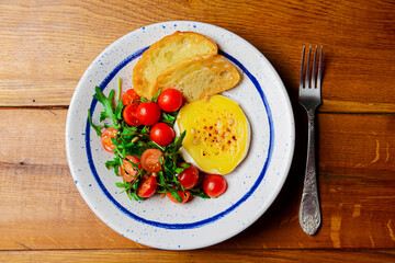 Baked camambert cheese with jam and fresh vegetable salad made from cherry tomatoes and green arugula