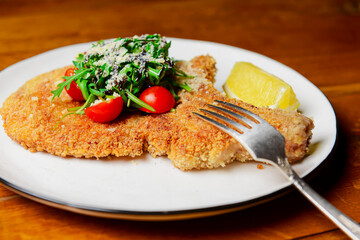 One deep fried fish bone steak with cherry tomatoes and fresh arugula on top.