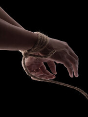 Person hands tied with rope isolated on black dark background, captive victim restrained