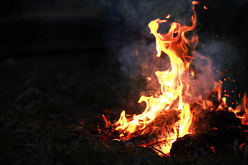 Burning red hot sparks fly from big fire. Burning coals, flaming particles flying off against black...