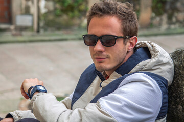 young man sitting on the stairs looking at his watch