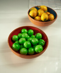 Fresh plum and maltese plum fruit in ceramic bowl on white table