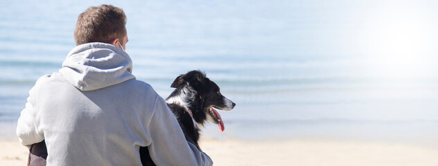 man in medical mask relaxed with his dog on the beach in the 'new normal'