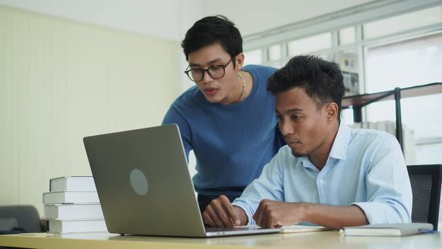 slow motion scene group of asian employee man advise and explaining to colleague about company's project on laptop screen about marketing strategy for multi ethnicity culture working concept	