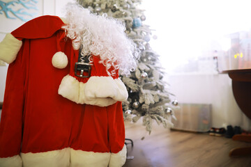 Santa costume hanging in white room. Chair with clothes from Santa Claus