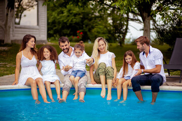 Large group of people sitting by the swimming pool.