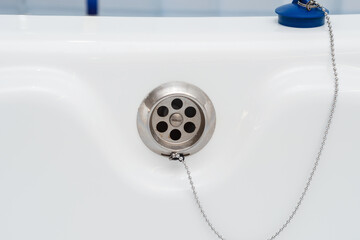 white bathtub with a hole for water drain and a blue stopper on a chain
