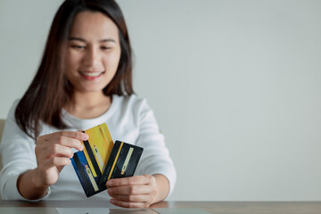 Woman holding and choosing credit card shown on the back of the card to use, Online payment concept.