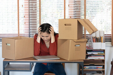 Female employee cried after losing her job during Covid-19 outbreak. Dejected fired office worker carrying a box full of belongings. Upset desperate female gets dismissal notice hiding crying face.