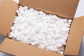 Lot of loose white Filler Shipping Packing Peanuts in cardboard box - obrazy, fototapety, plakaty