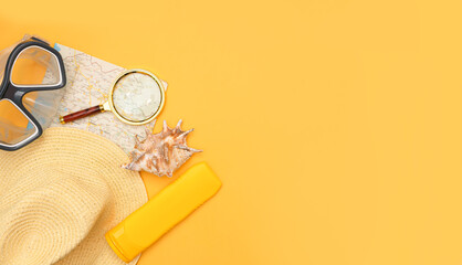 Swimming mask, hat, map, magnifier, sunblock and shell on a yellow background. The concept of choosing a place for rest, vacation at sea, active rest. Place for your text, design. top view, copy space
