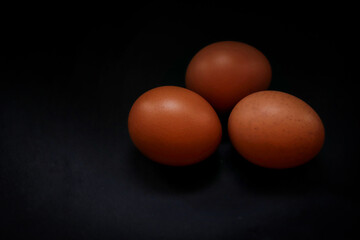 Many chicken eggs lie on a dark background