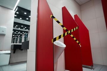 Graphic background image of public bathroom interior with toilet stall taped off for social...