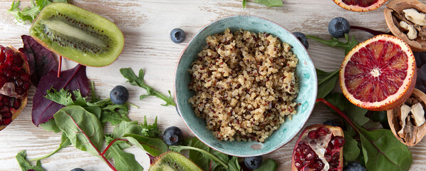 flat lay blue bowl with quinoa, kiwi, oranges, blueberries on wooden table