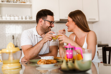 Young couple having breakfast at the table in the kitchen.