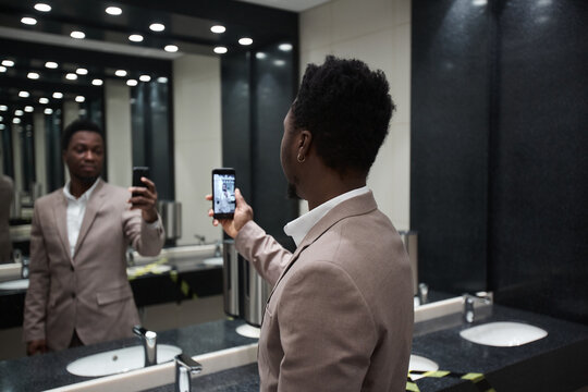 Portrait Of African-American Businessman Taking Mirror Selfie In Public Restroom, Copy Space