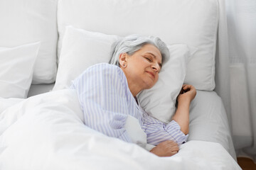 old age and people concept - senior woman sleeping in bed at home bedroom