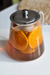 Tea pot on white table - transparent teapot witd double wall glass on white backgrouhd morning routine man's care healthy lifestyle fruit tea citrus orange for breakfast