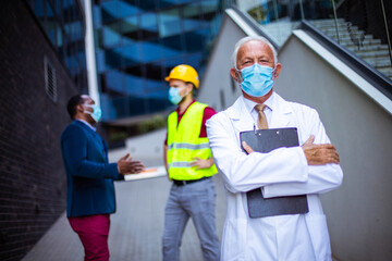 Business man, doctor and engineer on street. Focus is on  man.