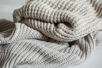 Cozy and warm knitted sweaters in pastel colors close-up.